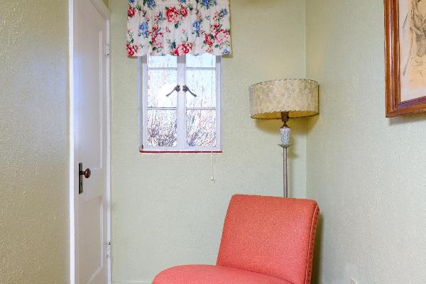 Each queen room has a comfortable area to sit and read or watch TV. Some rooms have original hardwood floors visible, like this one in Room 11.