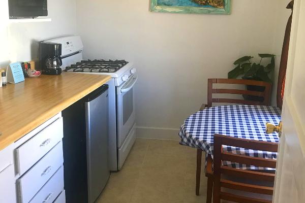 Kitchen with microwave, refrigerator, oven, stove & seating for two.