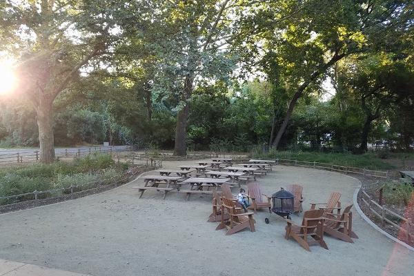 The courtyard features 10 picnic tables and 6 adirondack chairs on decomposed granite, surrounded by a native plant garden and mature trees. 
